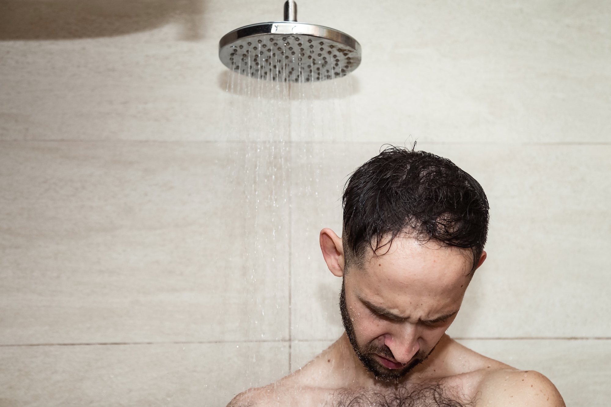 Man under low power shower sad